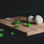 garlic bulb spinach leaves on cutting board